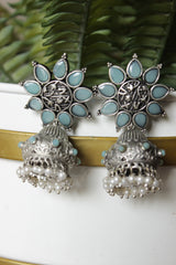 Turquoise Glass Stones Embedded Silver Finish Flower Motif Dangler Jhumka Earrings in Brass